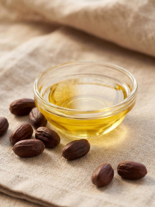 Golden jojoba oil in glass dish with jojoba seeds