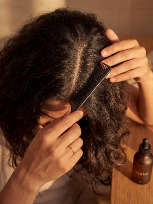 Parting hair with rat-tail comb, Atorisé bottle nearby